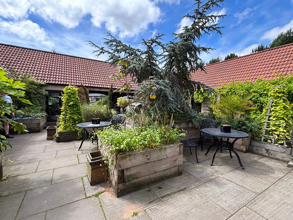 A garden with tables and chairs surrounded by plants at Kingfisher Hut in Swallownest near Sheffield