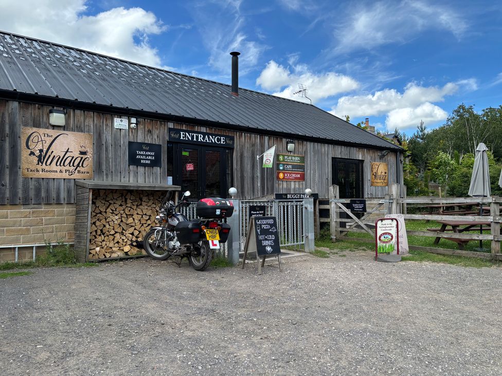 A wooden building with a motorcycle outside at The Vintage Tack Room and Play Barn in Swallownest near Sheffield