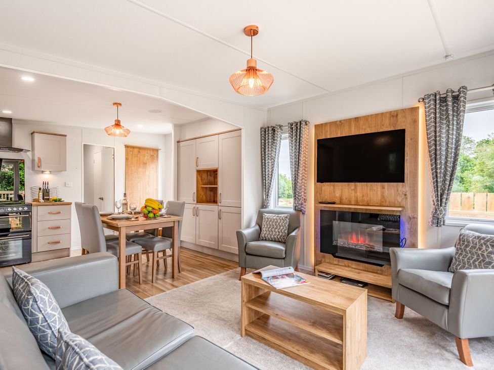 A living room with a sofa, chairs, table, and television at Caistor Spa in Louth