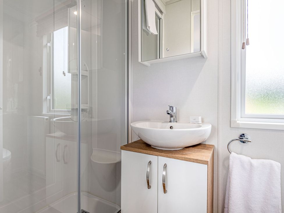 A bathroom with a shower, sink, and mirror at Caistor Spa in Louth