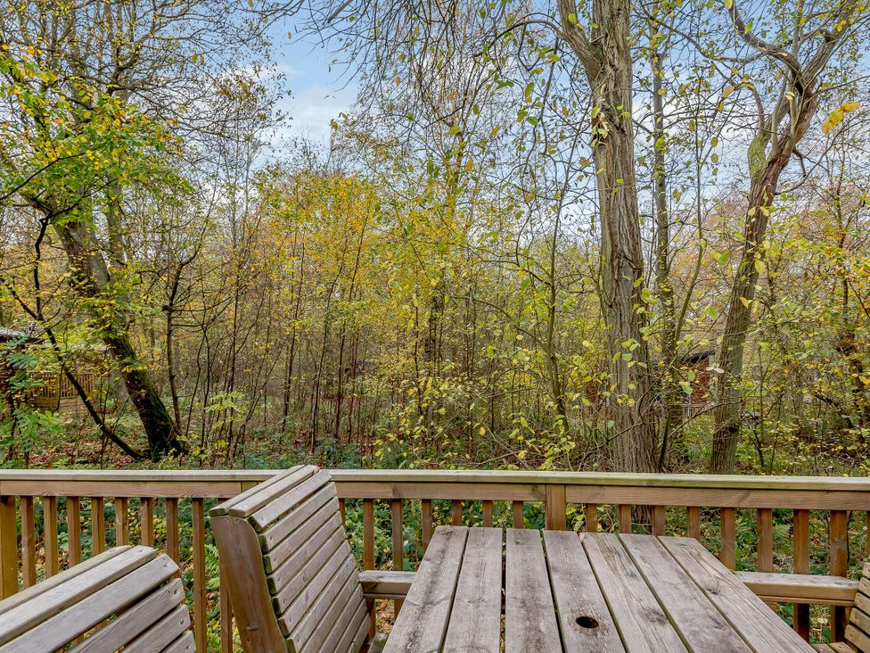 A deck area with a table and benches overlooking trees at Alford Spa, Louth