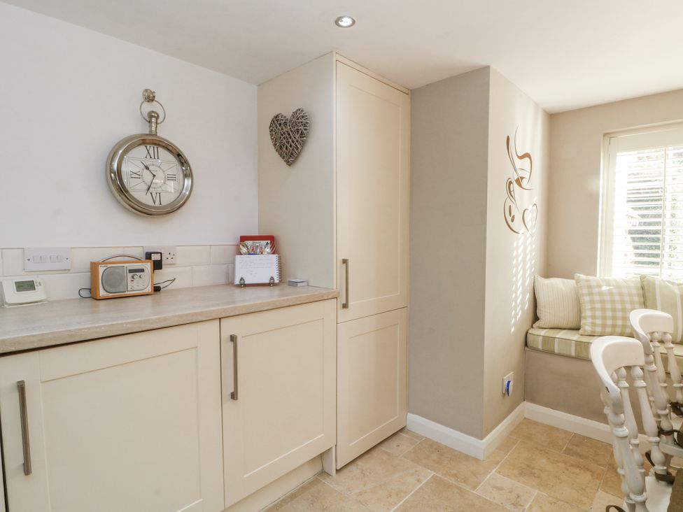 A kitchen with a clock and seating area at Curlew Cottage in Lower Peover, Cheshire