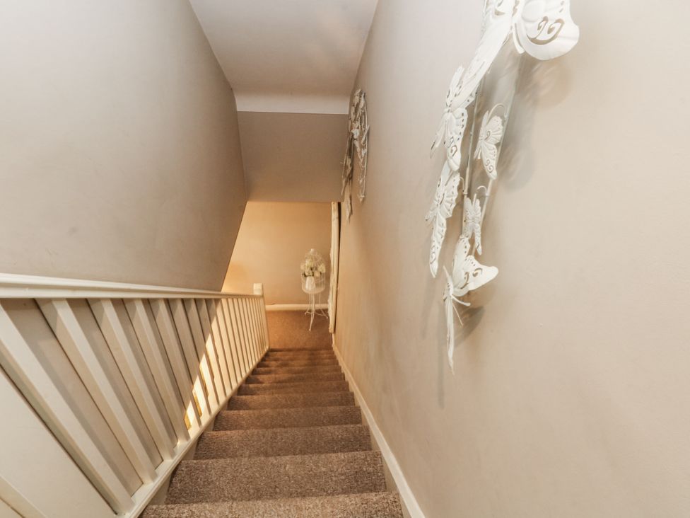 A staircase with a decorative wall and carpet at Curlew Cottage in Lower Peover, Cheshire