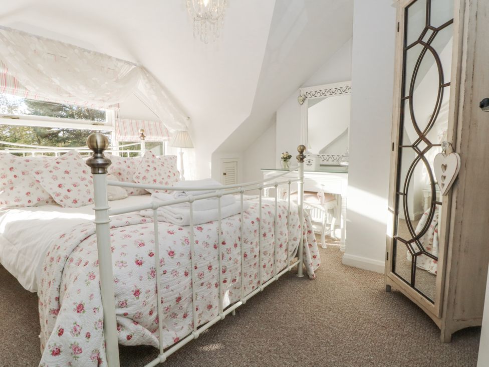 A bedroom with a bed, wardrobe, and desk at Curlew Cottage in Lower Peover, Cheshire