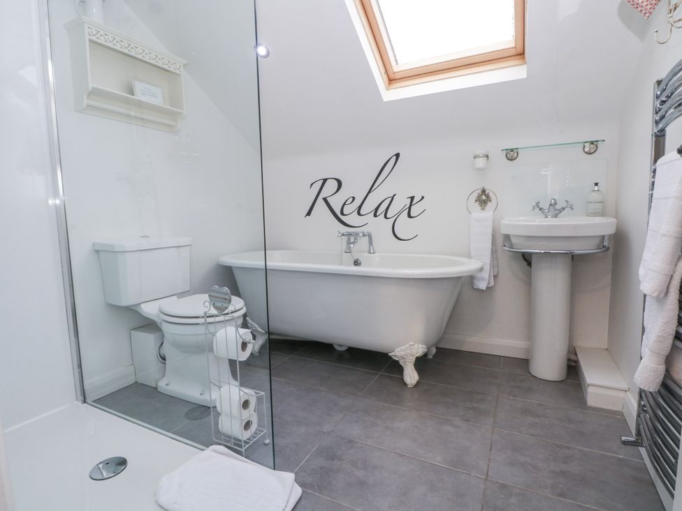 A bathroom with a bathtub, toilet, and sink at Curlew Cottage, Lower Peover, Cheshire