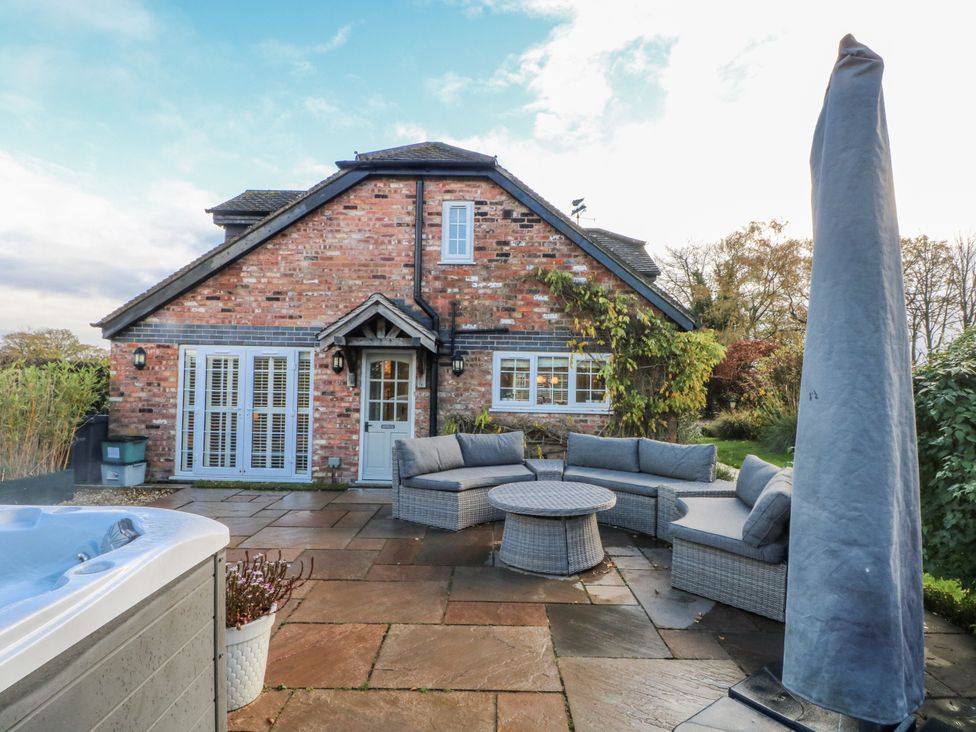 A garden with outdoor seating and a hot tub at Curlew Cottage in Lower Peover, Cheshire