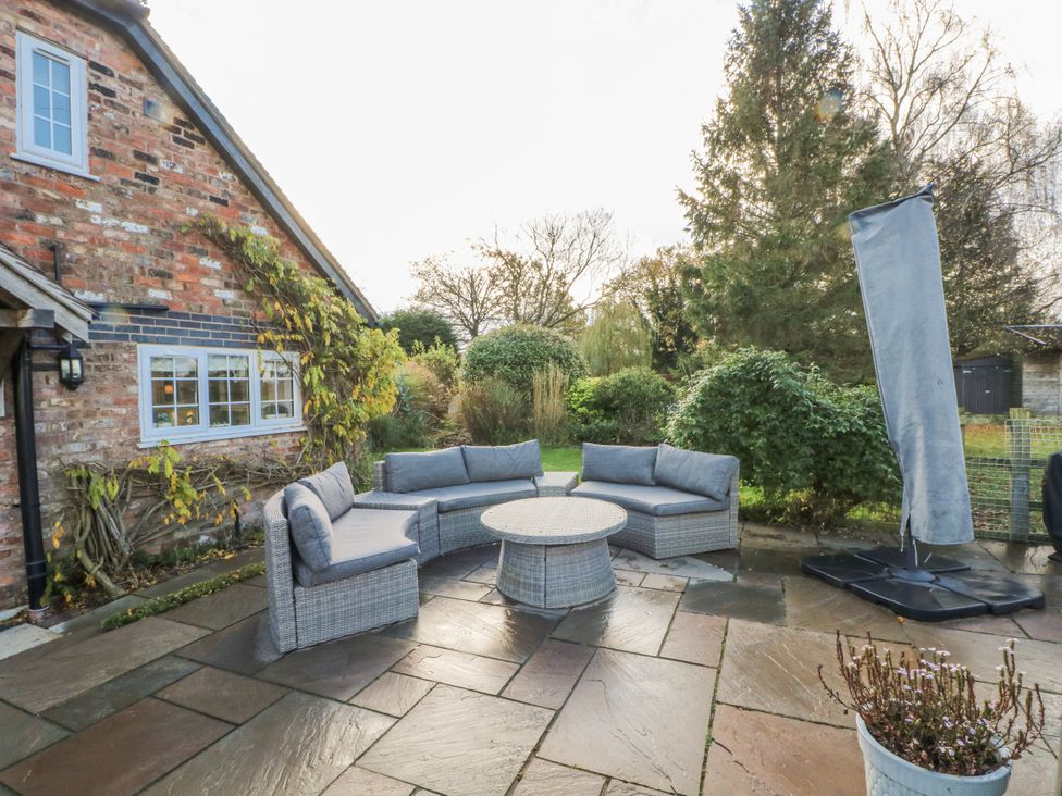 A garden with a sofa and a table at Curlew Cottage in Lower Peover, Cheshire