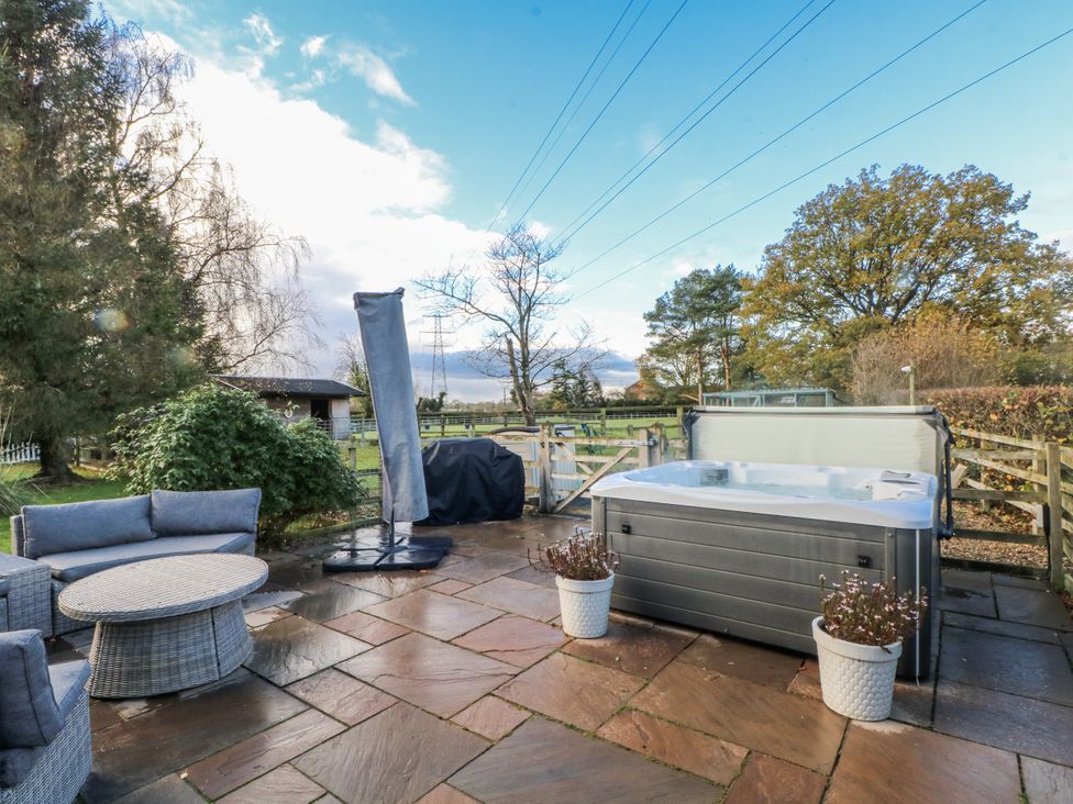 A garden with a hot tub and outdoor furniture at Curlew Cottage in Lower Peover, Cheshire