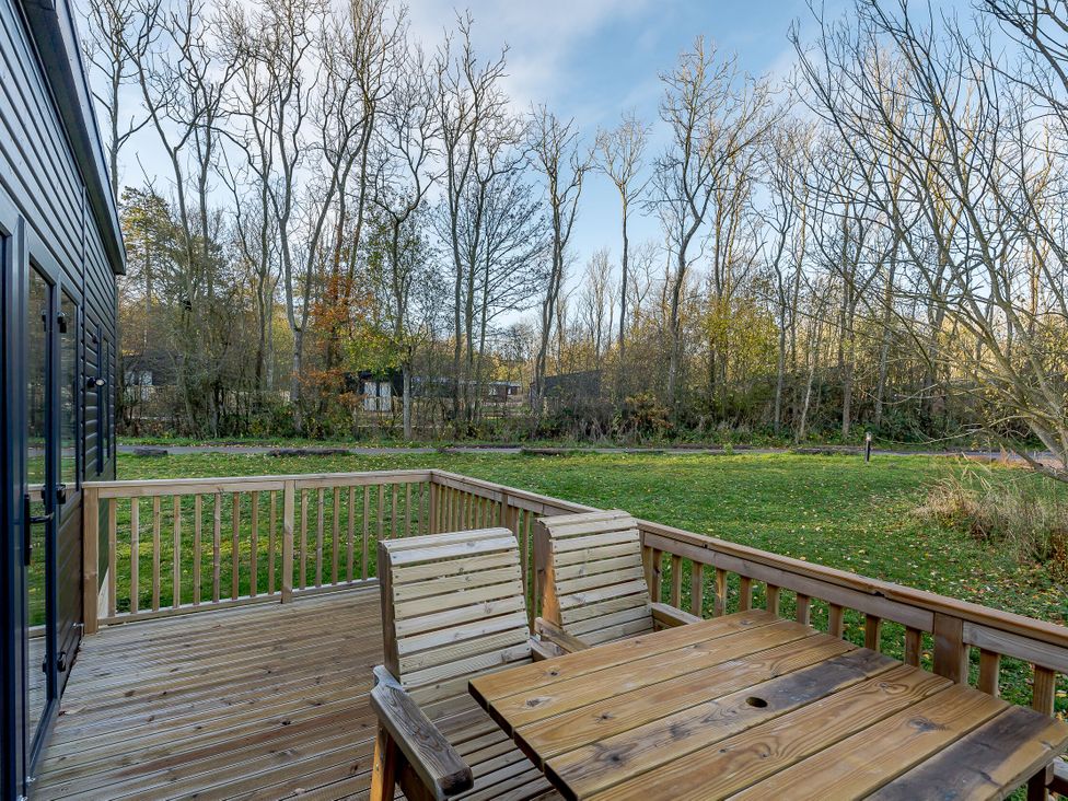 A deck with wooden furniture overlooking trees at Horncastle Spa in Louth