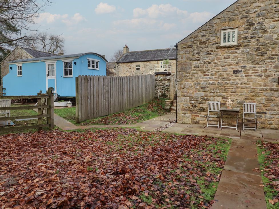 A garden with a blue cabin and furniture at Meadows in Hexham
