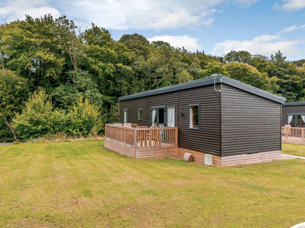 A cabin with decking surrounded by grass and trees at The Kinder Spa Louth