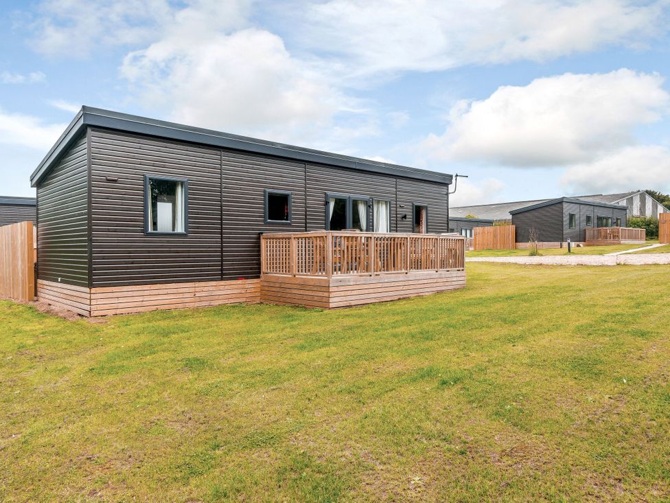 A lodge with a decking area and grass at The Kinder Spa in Louth