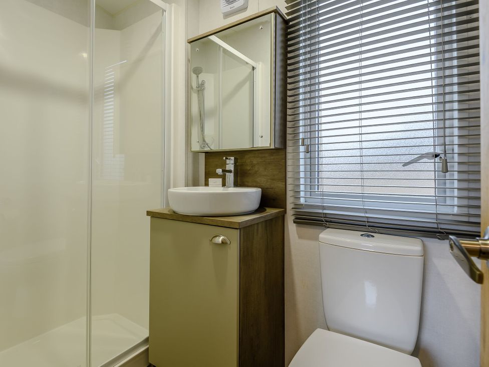 A bathroom with a shower, sink, mirror, and toilet at The Kinder Spa in Louth