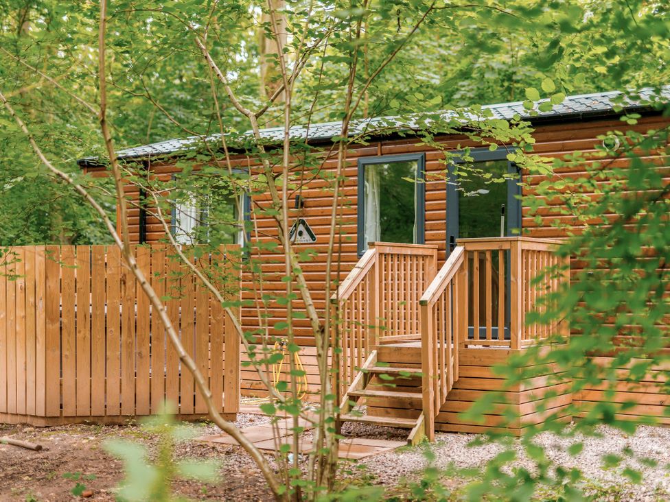 A wooden cabin with stairs and a fence in the woods at Alford Spa (Pet) Louth
