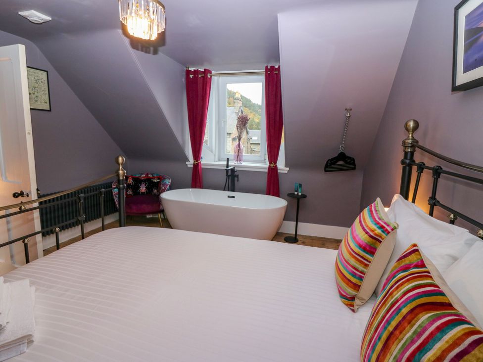 A bedroom with a bed and a bathtub at Lindean Ballater