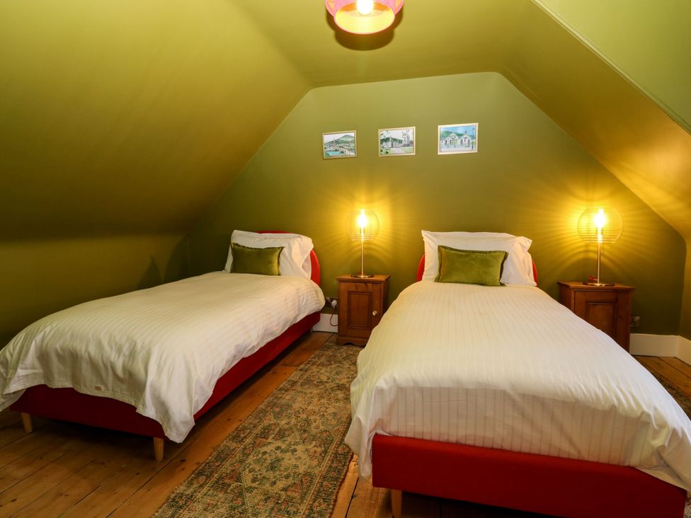 A bedroom with two beds and artwork on the wall at Lindean in Ballater