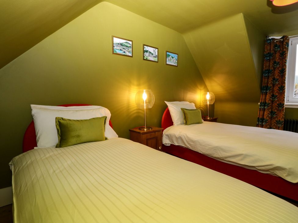 A bedroom with two single beds and a lamp at Lindean in Ballater