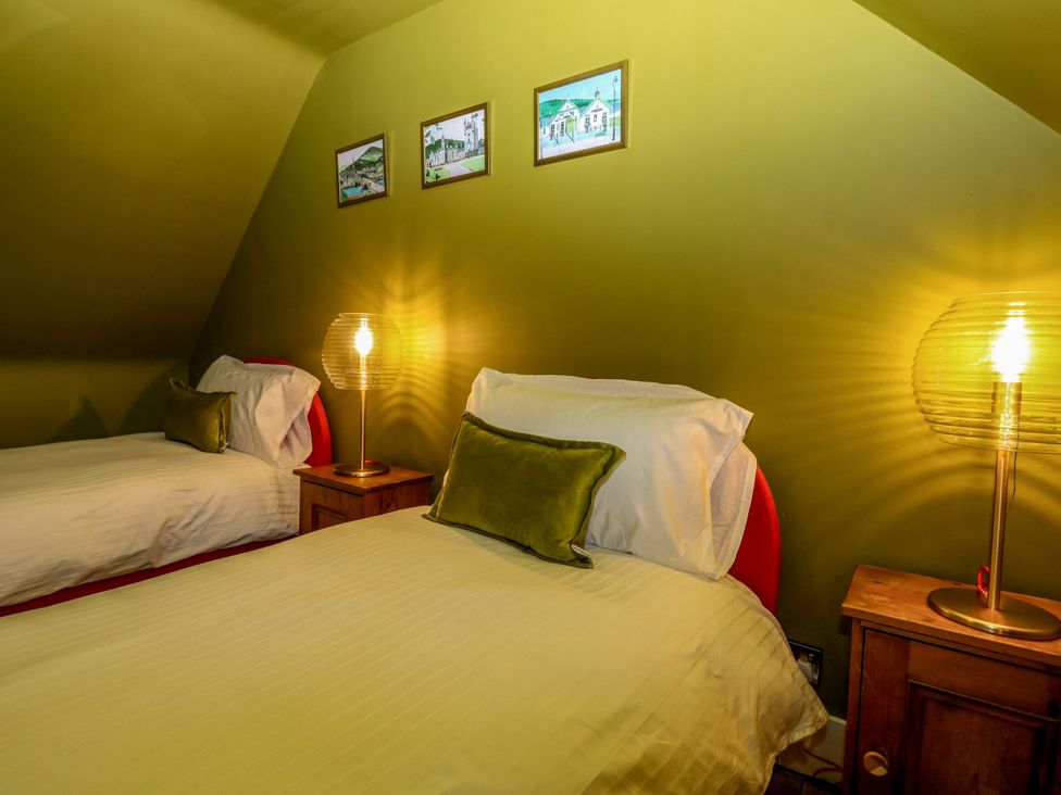 A bedroom with two beds and lamps at Lindean in Ballater