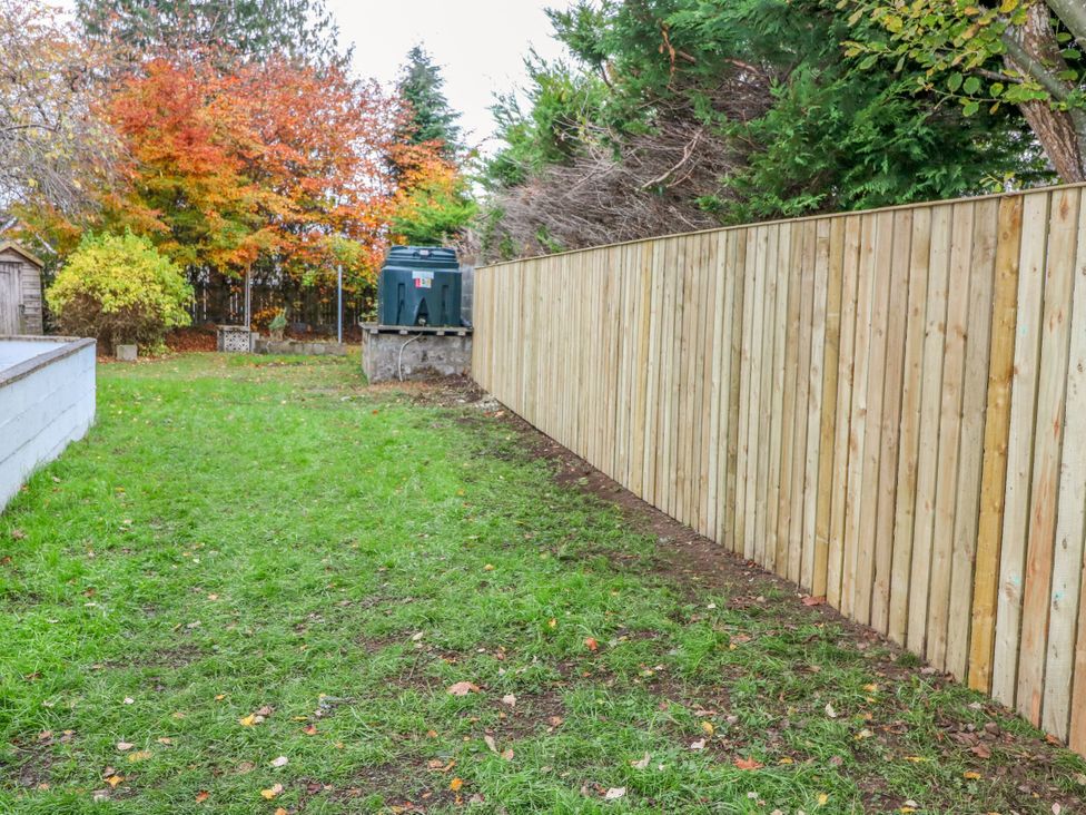 A garden with a wooden fence and a shed at Lindean in Ballater