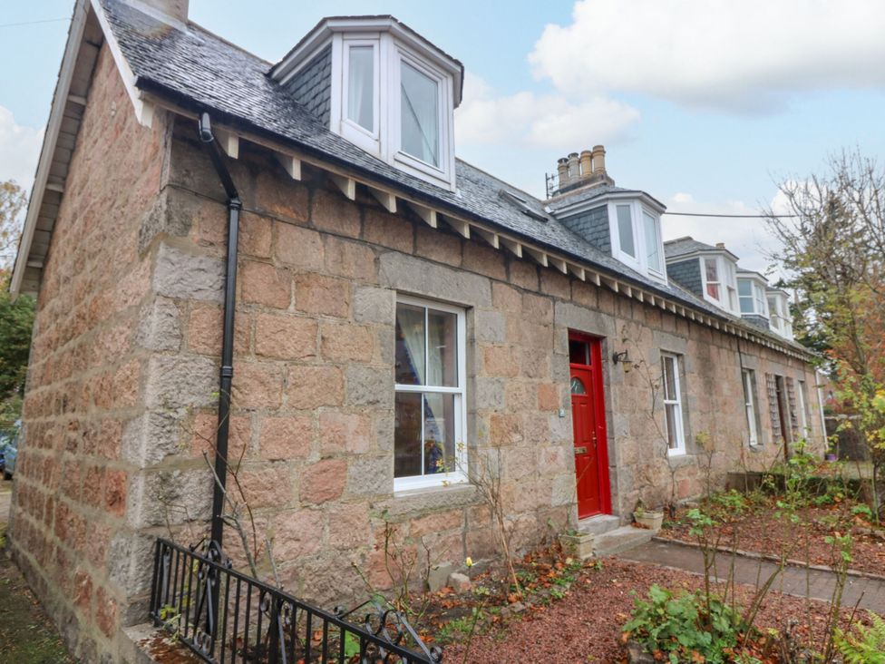 A stone house with a red door and windows at Lindean in Ballater