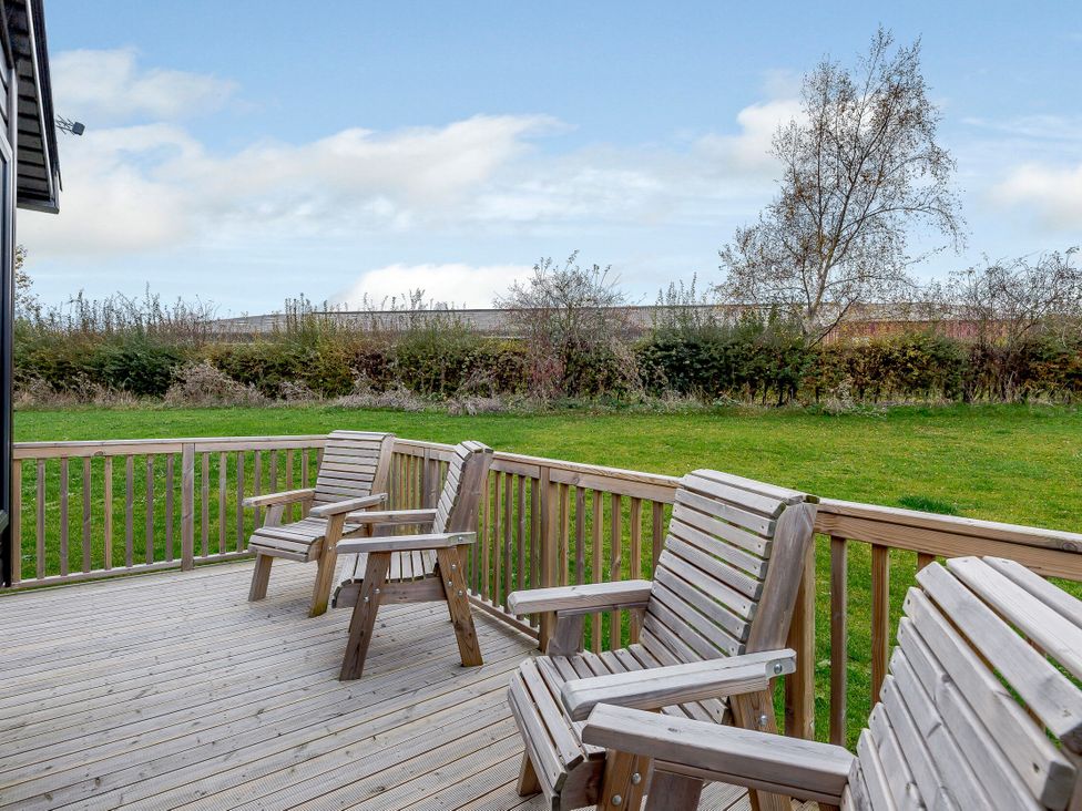 An outdoor area with wooden chairs on a deck at Alford WF in Louth