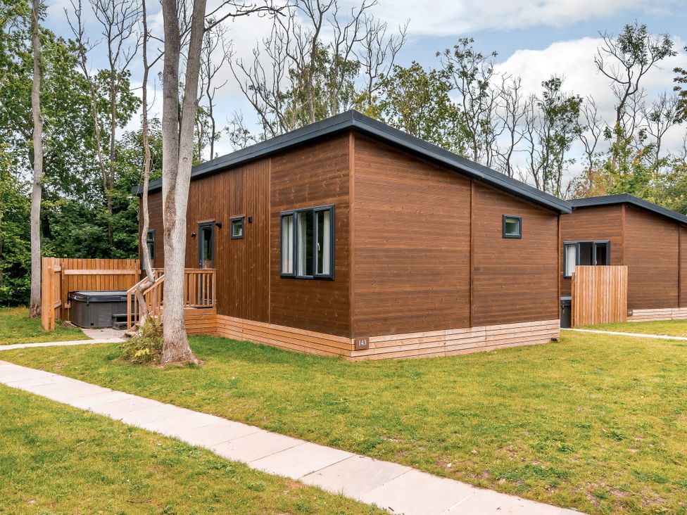 A wooden cabin with hot tub and trees at Stamford Spa in Louth