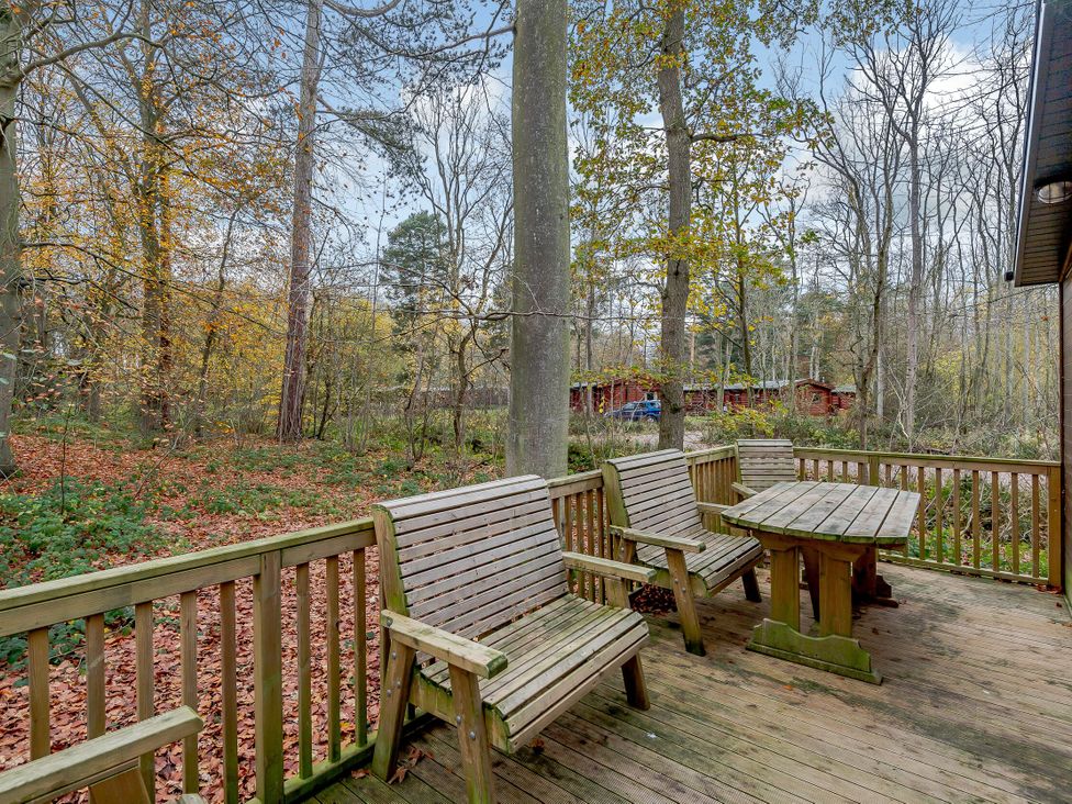 An outdoor area with wooden furniture and trees at Stamford Spa in Louth
