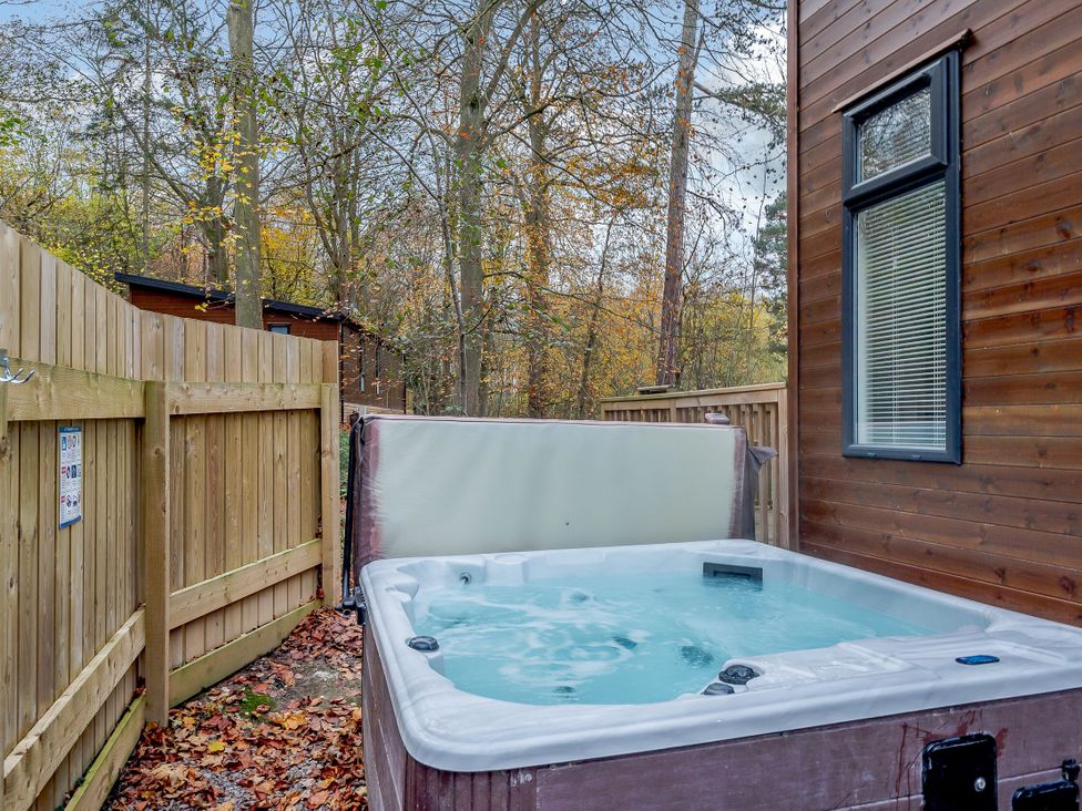 An outdoor space featuring a hot tub with a wooden fence at Stamford Spa in Louth