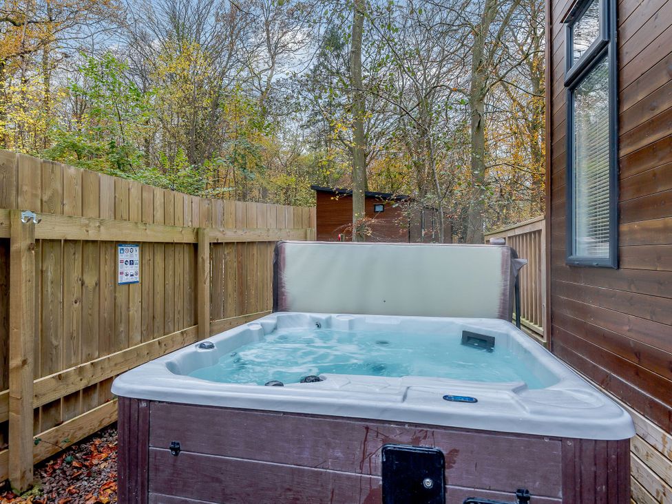 A hot tub surrounded by a wooden fence and trees at Stamford Spa (Pet) Louth