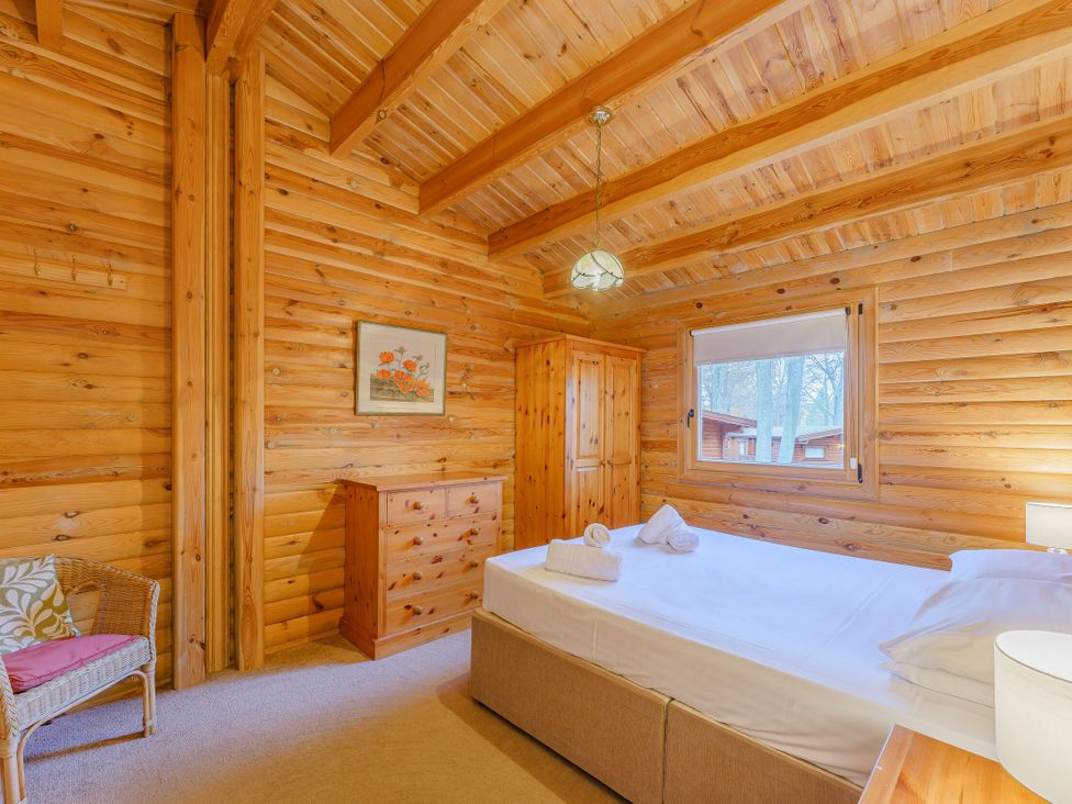 A bedroom with a bed, dresser, and chair at Cedar Lodge (Pet) in Louth