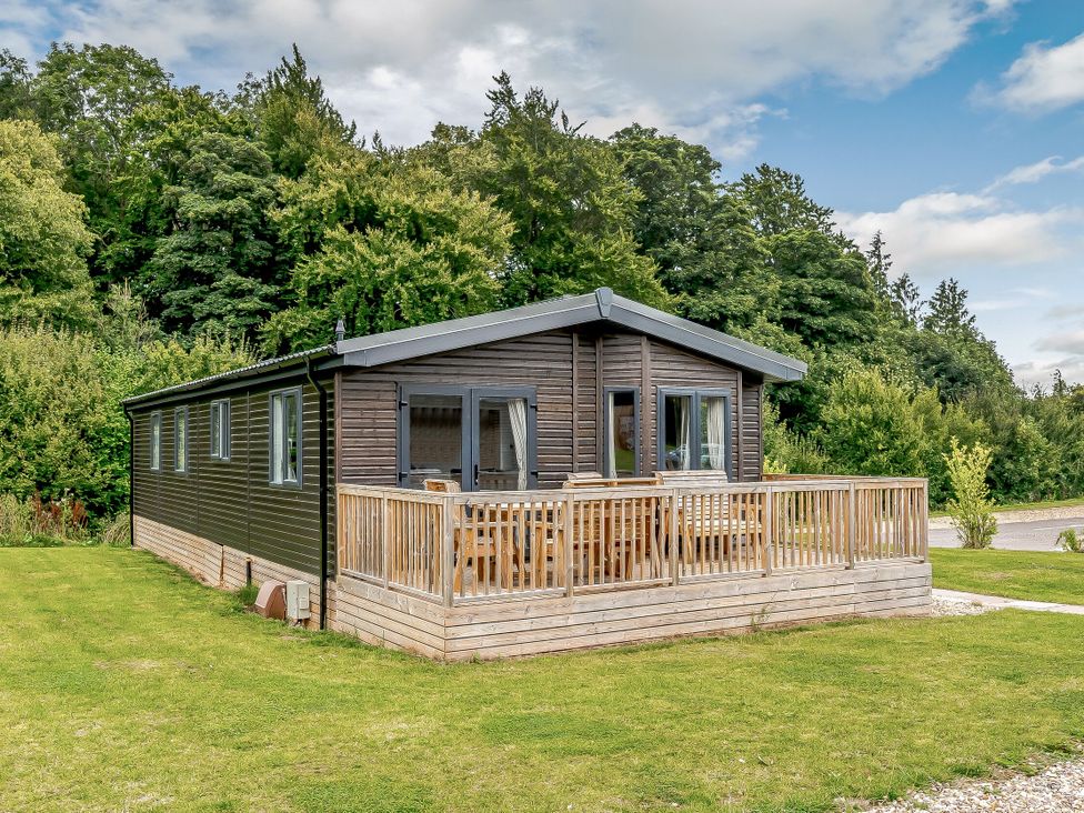 A cabin with a wooden deck and surrounding grass at Elsham Lodge (Pet) Louth