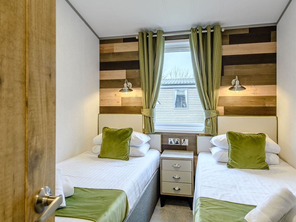 A bedroom with two single beds and a nightstand at Elsham Lodge (Pet) Louth