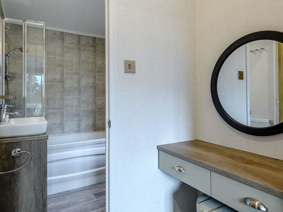 A bathroom with a shower, bathtub, sink and mirror at Elsham Lodge (Pet) in Louth