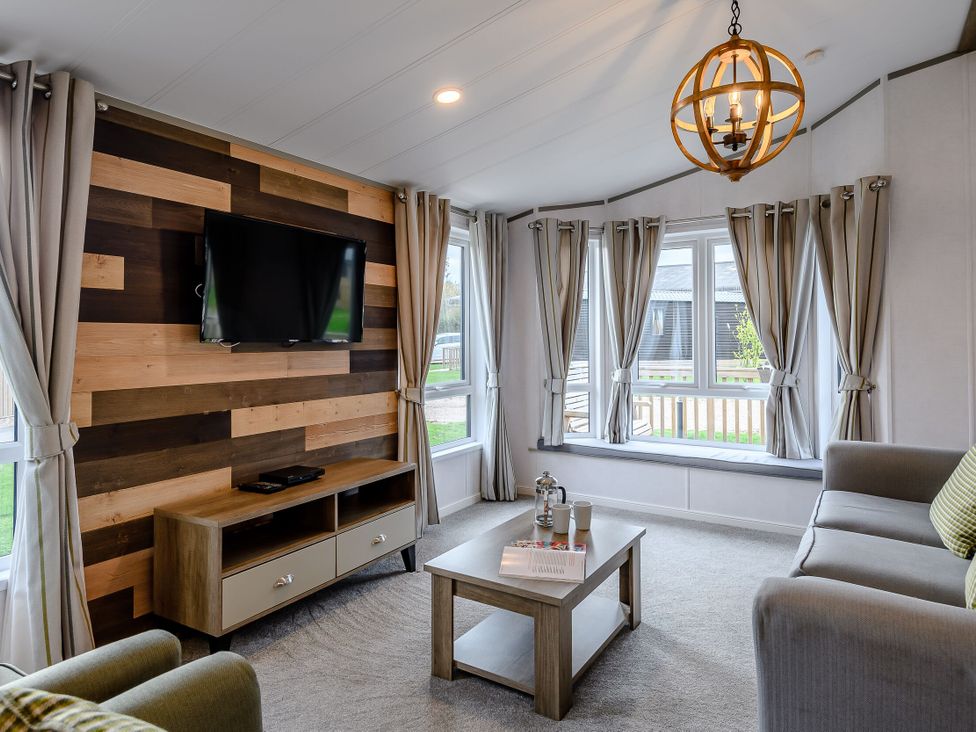 A living room with a television mounted on the wall at Elsham Lodge (Pet) in Louth