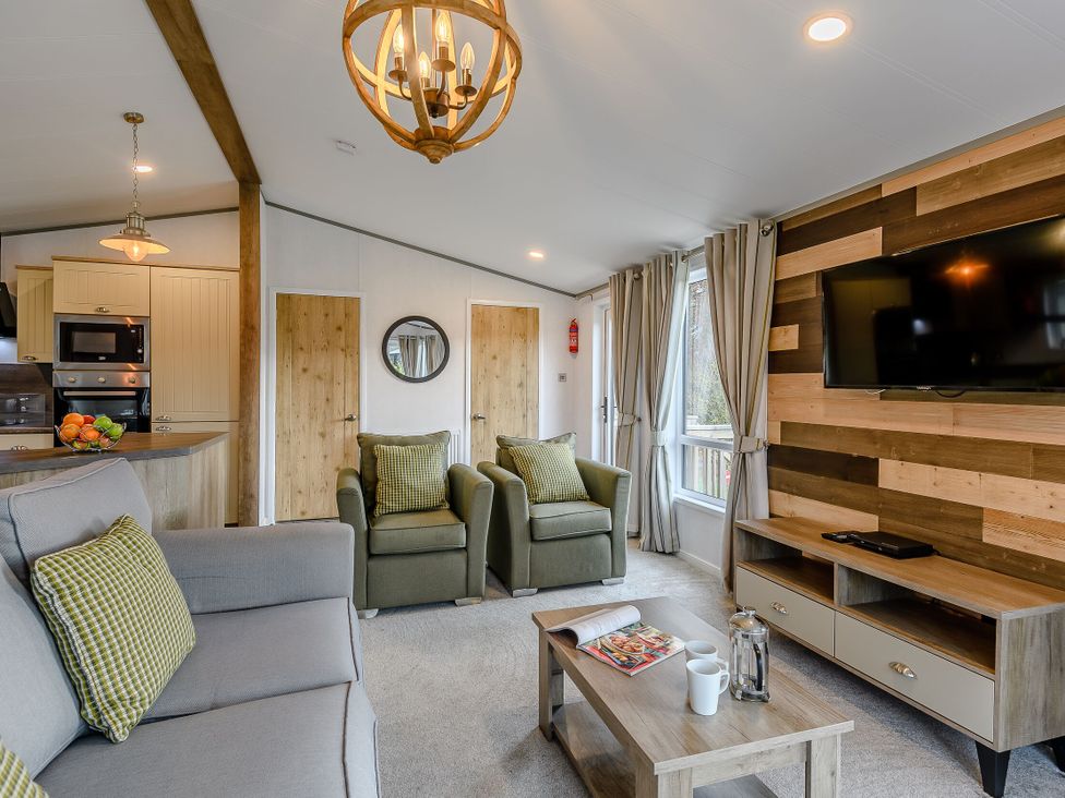 A living room with a sofa, armchairs, and television at Elsham Lodge (Pet) Louth