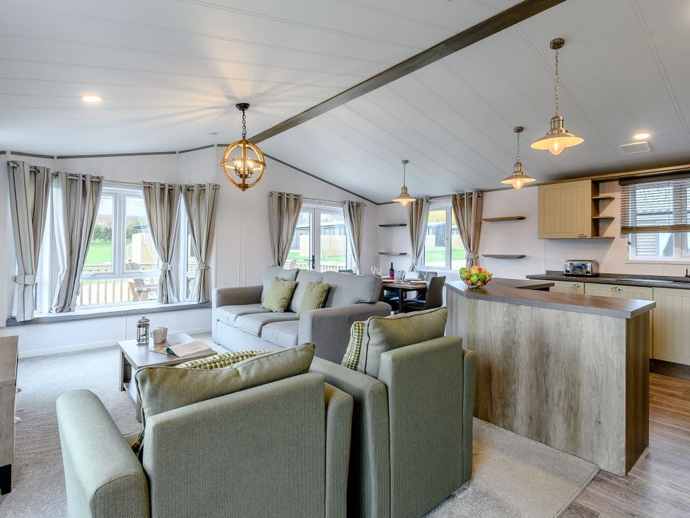 A living room with a sofa and kitchen counter at Elsham Lodge (Pet) in Louth