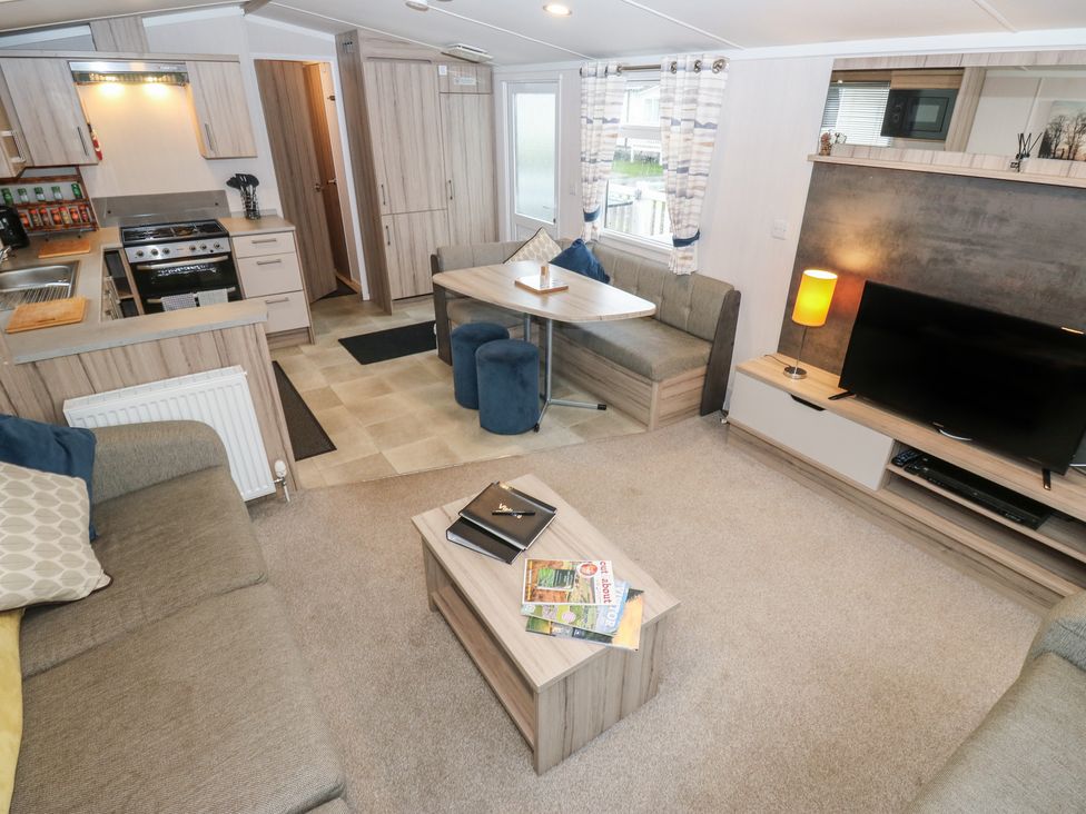 A living room with a kitchen area and seating at Woodland View 