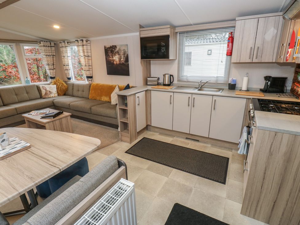 A living room and kitchen area with seating and appliances at Woodland View