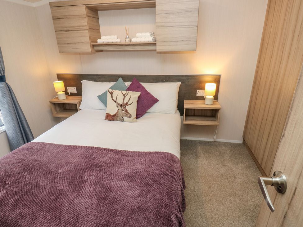 A bedroom with a bed and bedside tables at Woodland View 
