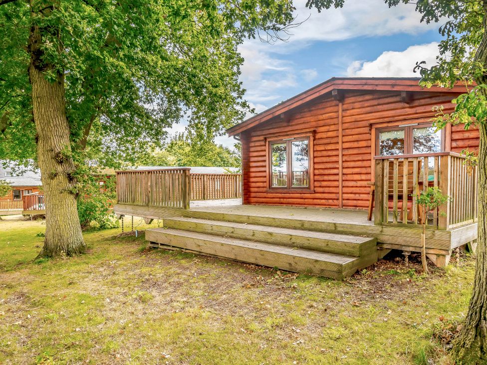 A wooden cabin with a deck and steps at Hazel Lodge in Louth