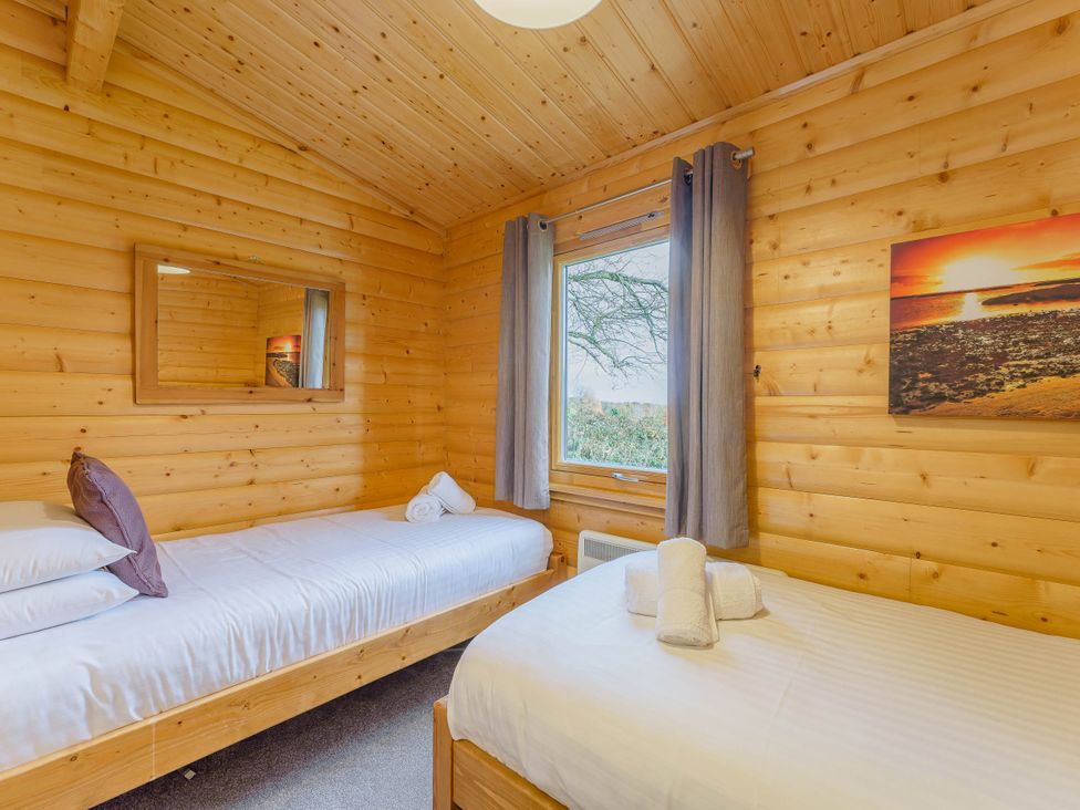 A bedroom with two beds and a window at Hazel Lodge in Louth