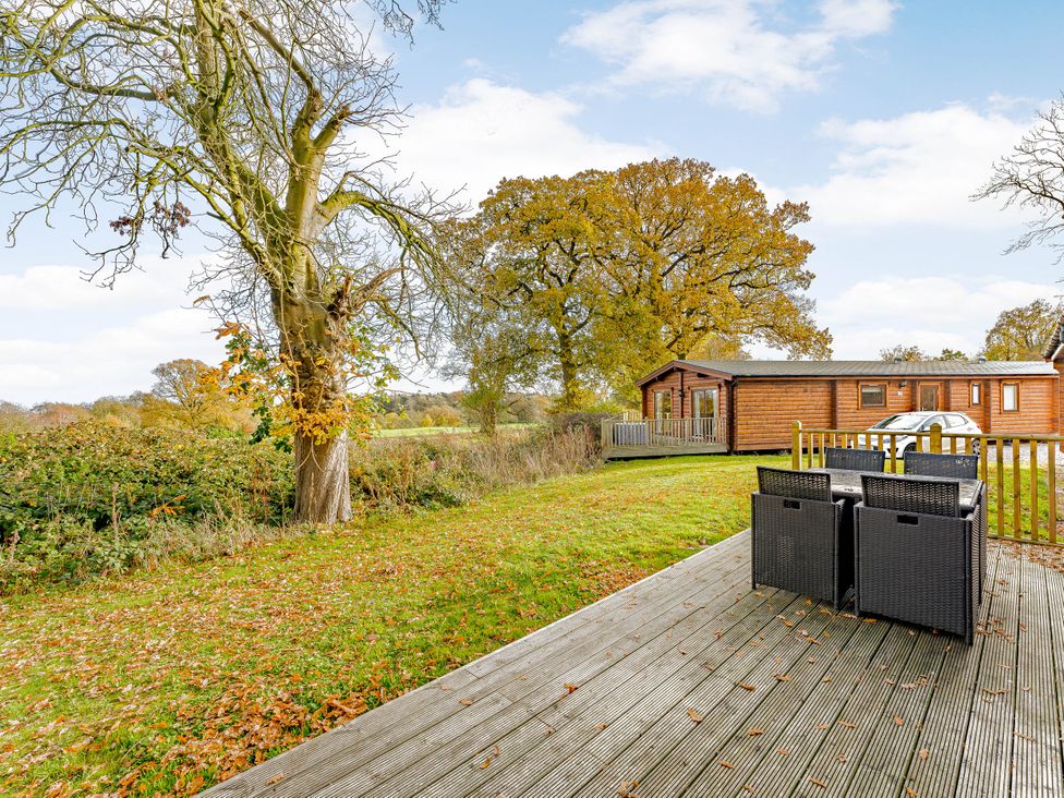 A deck with chairs and trees at Hazel Lodge in Louth