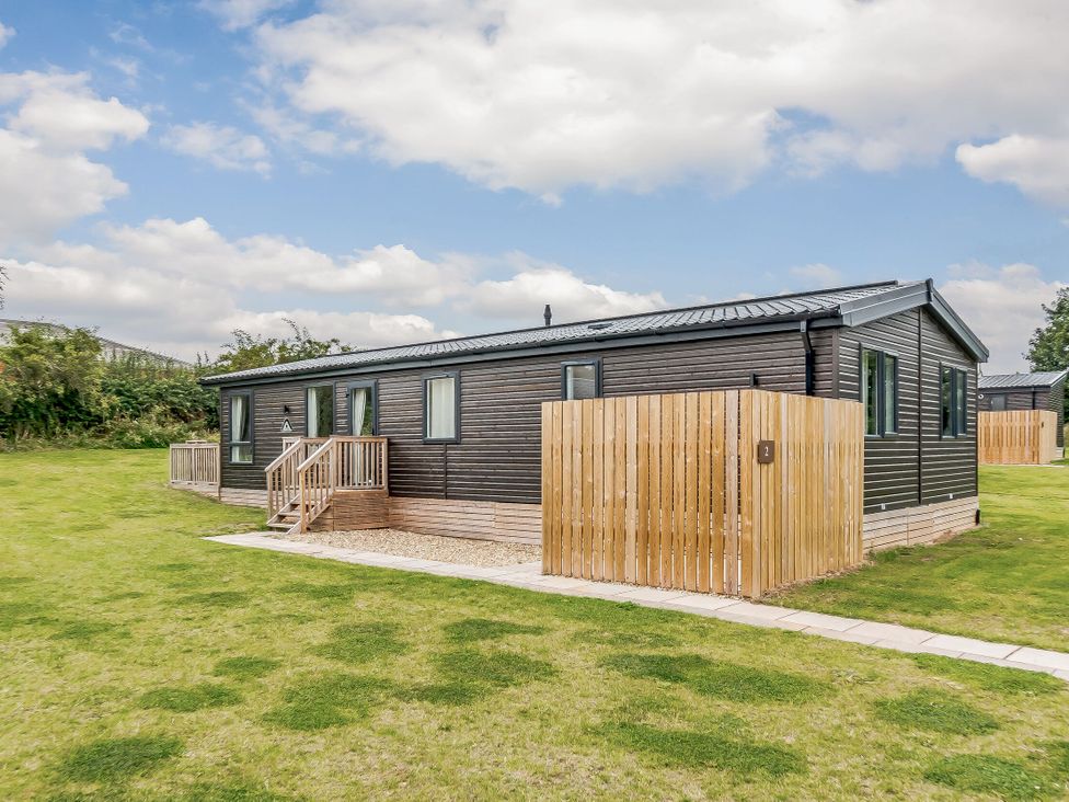 A modular building with a lawn and fence at Brayford Lodge in Louth