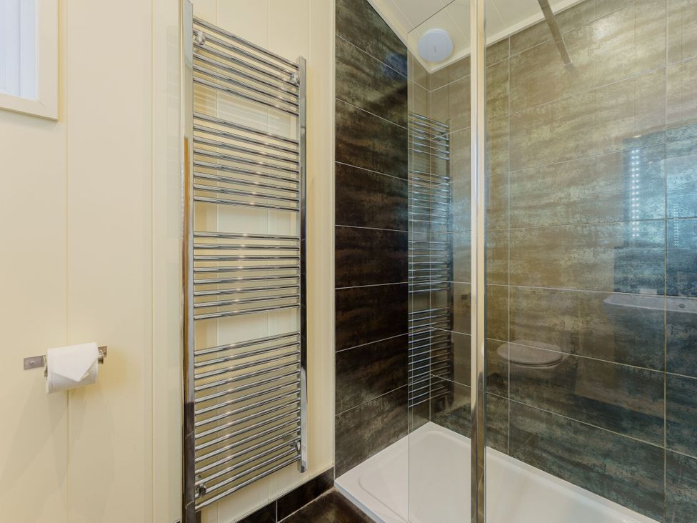 A bathroom with a shower and towel rail at Retreat Lodge 4 in Louth