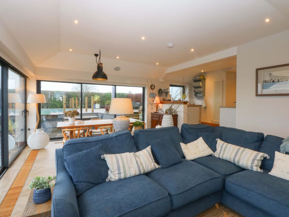 A living room with a sofa and dining area at Bryn Mor Cottage in Mynytho near Llanbedrog