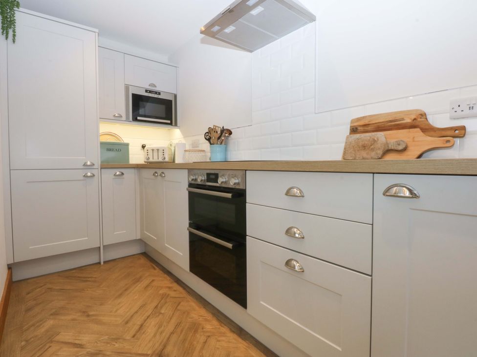 A kitchen with appliances and cabinets at Bryn Mor Cottage Mynytho near Llanbedrog