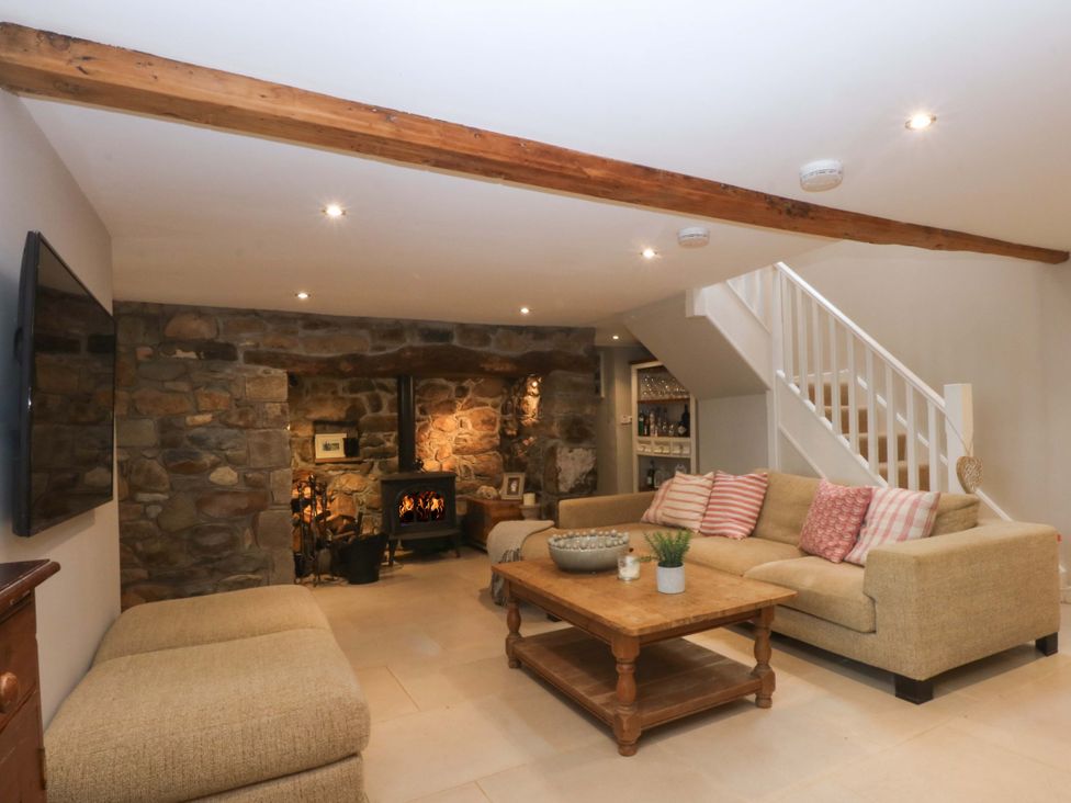 A living room with a sofa, coffee table and fireplace at Bryn Mor Cottage in Mynytho near Llanbedrog