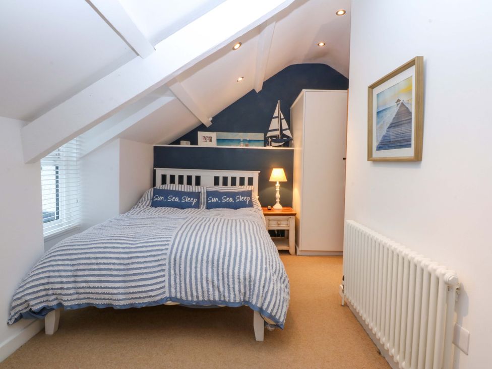 A bedroom with a bed and lamp at Bryn Mor Cottage in Mynytho near Llanbedrog