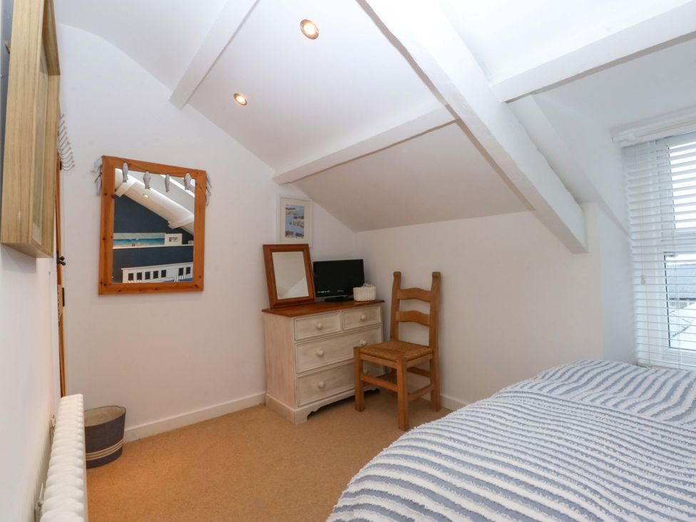 A bedroom with a chair and a dresser at Bryn Mor Cottage, Mynytho near Llanbedrog