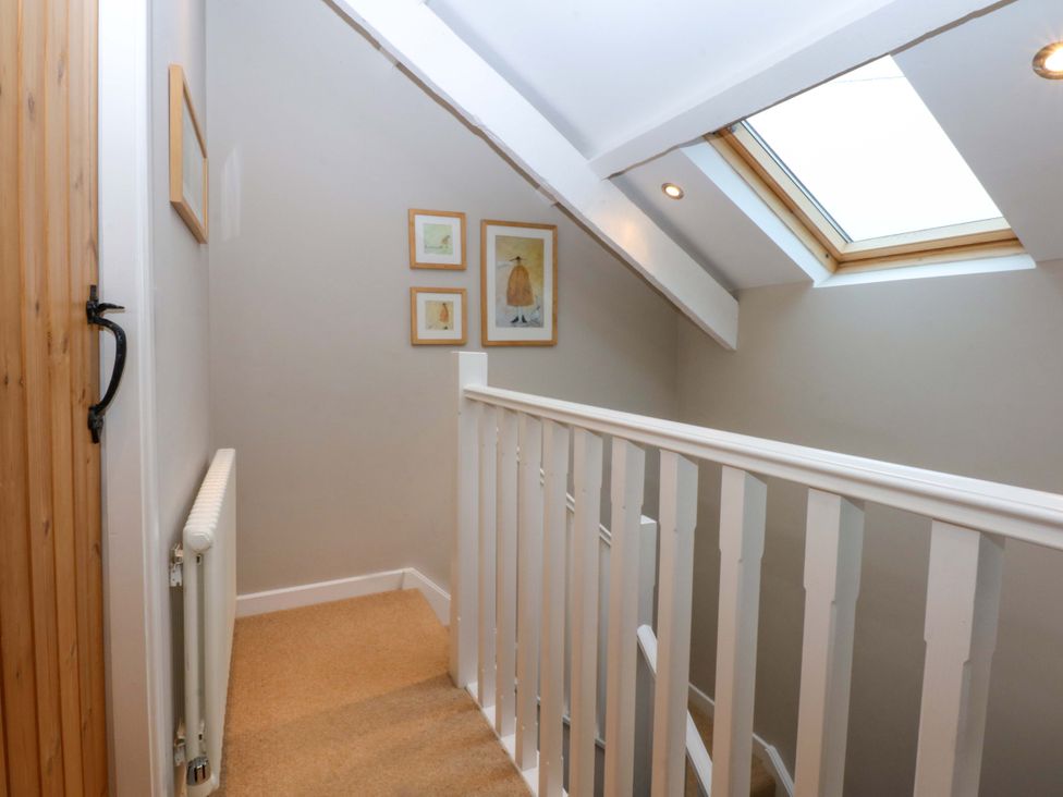 A hallway with a staircase and stair railing at Bryn Mor Cottage in Mynytho near Llanbedrog